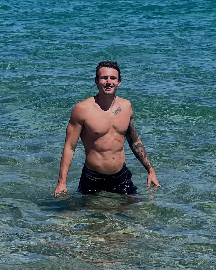 Tyler Chessa smiling, standing in the ocean